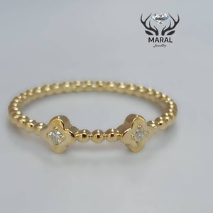 May include: A gold ring with a beaded band and two small, four-leaf clover designs with a single diamond in each.