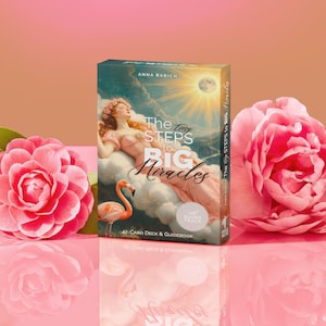 Puede incluir: Un mazo de cartas y una guía titulada "The Tiny Steps to Big Miracles" de Anna Babich. La caja presenta una ilustración de una mujer en una nube con un flamenco. Rosas rosas enmarcan la caja sobre una superficie rosa reflectante.