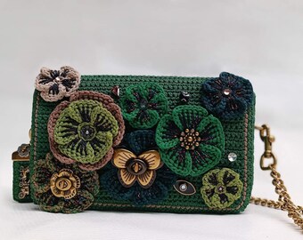 May include: A green crocheted handbag with a chain strap and floral embellishments. The bag features a variety of colorful flowers, including green, brown, and blue.