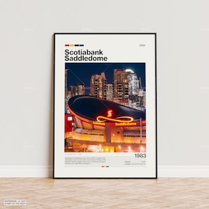 May include: A framed poster featuring the Scotiabank Saddledome arena in Calgary, Alberta, at night. The arena's neon sign glows red, and the city skyline is visible in the background. The poster includes the text "Scotiabank Saddledome" and "1983".