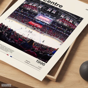 May include: A framed print featuring an aerial view of a hockey game at the Molson Centre in Montreal, Canada. The arena is filled with spectators in red seating. The print includes the year 1996, capacity 21,000, and location coordinates.
