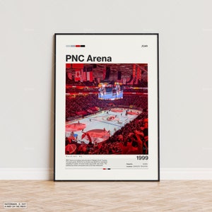 May include: A framed print featuring the PNC Arena in Raleigh, NC. The image shows a hockey game in progress, with a large crowd and the arena's interior. The text "PNC Arena" and "1999" are visible.