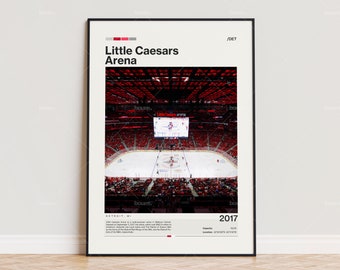 May include: A framed poster featuring the Little Caesars Arena in Detroit, MI. The image shows a hockey game in progress, with a red and white color scheme. Text on the poster includes "Little Caesars Arena" and "2017".
