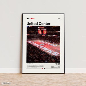 Op de afbeelding: Een ingelijste poster met de United Center arena in Chicago, Illinois. De afbeelding toont een hockeywedstrijd met het logo van de Chicago Blackhawks op het ijs. De poster bevat de tekst "United Center" en het jaar "1994".