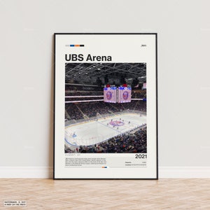 May include: A framed poster featuring the UBS Arena, a multi-purpose indoor arena in Elmont, NY. The image shows a hockey game in progress, with the arena's name prominently displayed. The poster includes the year 2021.