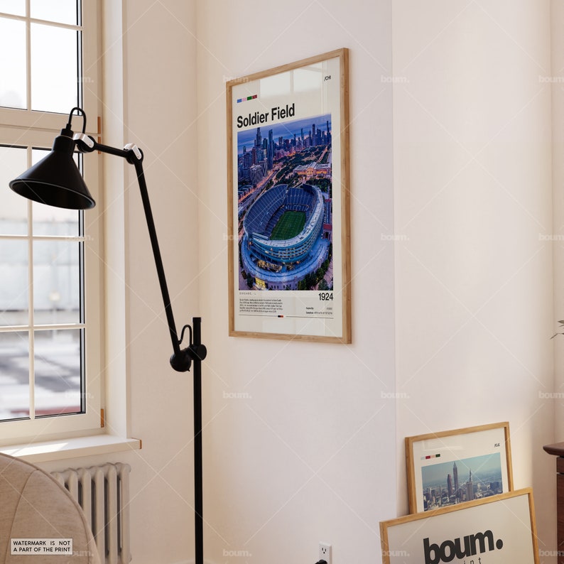 May include: A framed poster featuring an aerial view of Soldier Field stadium in Chicago. The poster has a wooden frame and includes the text "Soldier Field" and the year "1924". The image shows the stadium's green field and surrounding city skyline.