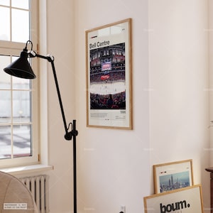 May include: A framed poster featuring the Bell Centre arena with the text "Bell Centre" at the top. The image shows a hockey game in progress, with the year "1996" at the bottom. The frame is a light wood color.