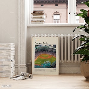 May include: A framed poster of Fenway Park, featuring an aerial view of the baseball stadium with a green field and red seating. The poster includes the text "Fenway Park" and "1912". The poster is displayed near a window.
