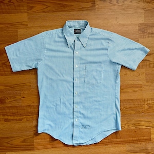 May include: A blue and white striped short-sleeved button-down shirt with a pocket on the left side.