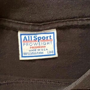 May include: A white tag with black text that reads "All Sport PROWEIGHT PRESHRUNK MADE IN U.S.A. 100%Cotton/Coton L(44)"
