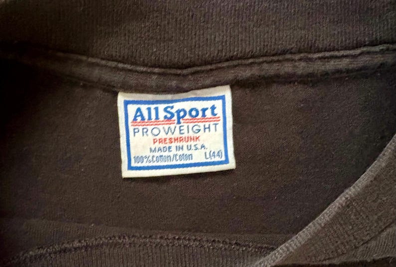 May include: A white tag with black text that reads "All Sport PROWEIGHT PRESHRUNK MADE IN U.S.A. 100%Cotton/Coton L(44)"