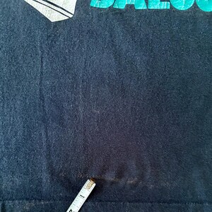 May include: A black t-shirt with a faded teal graphic that says "SALOON".