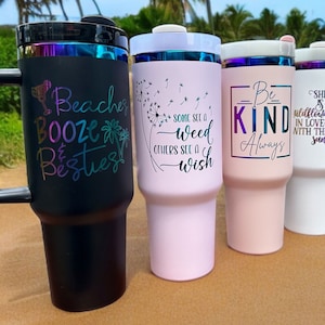 May include: Three stainless steel tumblers with different designs. The first tumbler is black with the text "Beaches Booze & Besties". The second tumbler is pink with the text "Some see a weed, others see a wish". The third tumbler is white with the text "Be Kind Always" and a sunflower graphic.