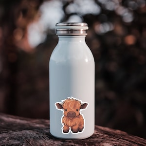 May include: A light blue insulated water bottle with a silver lid. A sticker of a cartoon Highland cow is on the front. The cow is brown with a fluffy coat and dark brown eyes. The bottle is approximately 8 inches tall.