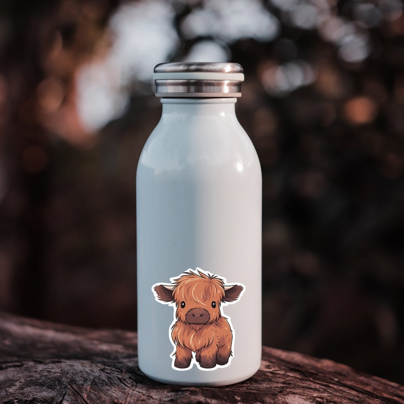 May include: A light blue insulated water bottle with a silver lid. A sticker of a cartoon Highland cow is on the front. The cow is brown with a fluffy coat and dark brown eyes. The bottle is approximately 8 inches tall.