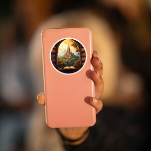 May include: A round sticker featuring a fantasy scene of a castle viewed through a window. The window is framed by bookshelves. The castle sits atop a green hill, with a book open in front of the window. The sticker is on a pink phone.