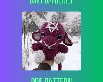 Könnte beinhalten: Ein gehäkeltes Plüschtier in Form eines lilafarbenen Baby-Baphomet mit einem Pentagramm auf der Brust. Das Spielzeug hat weiße Akzente und große, runde Augen. Das Spielzeug wird in einer Hand vor einem schneebedeckten Hintergrund gehalten. Der Text "BABY BAPHOMET" befindet sich oben im Bild und "PDF PATTERN" unten.