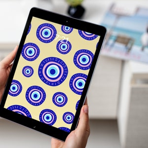 May include: A tablet computer displaying a digital wallpaper with a pattern of blue and pink evil eyes on a yellow background.