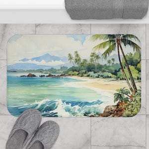 May include: A rectangular bath mat featuring a watercolor painting of a tropical beach scene. The artwork depicts a sandy shore, turquoise water, palm trees, and mountains in the background. Gray slippers are in the foreground.