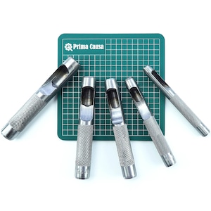 May include: Set of six silver metal leather hole punches on a green cutting mat. The punches are different sizes and have a textured grip.