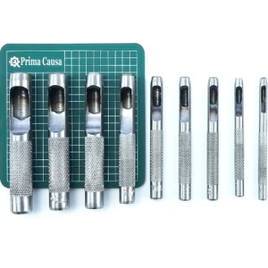 May include: Set of nine silver leather hole punches on a green cutting mat. The punches are different sizes and have a textured grip.
