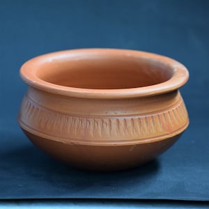 Puede incluir: Un cuenco de terracota con un patrón decorativo alrededor del borde. El cuenco está hecho de arcilla y tiene un color marrón natural.