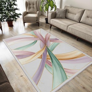 Può includere: Tappeto rettangolare con sfondo bianco e un design di nastri fluenti nei colori pastello: lavanda, verde e pesca. I nastri sono delineati in oro, creando un aspetto elegante e artistico. Il tappeto è bordato con un bordo dorato.