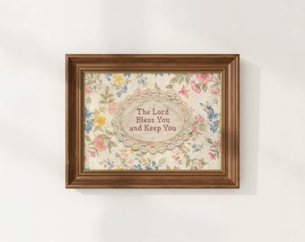 Könnte beinhalten: Ein gerahmter Blumendruck mit dem Text "The Lord Bless You and Keep You". Der Druck hat einen cremefarbenen Hintergrund mit einem floralen Muster in Rosa, Blau und Gelb. Der Rahmen ist warmbraun.
