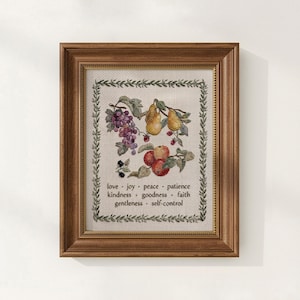 May include: Framed cross-stitch artwork featuring a still life of fruit, including grapes, pears, and apples. The artwork is surrounded by a border of greenery and includes the words "love, joy, peace, patience, kindness, goodness, faith, gentleness, self-control."