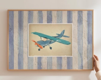 May include: A framed artwork featuring a vintage-style airplane illustration. The airplane is blue with teal wings and an orange propeller, set against a beige background. The frame has a blue and white striped pattern.