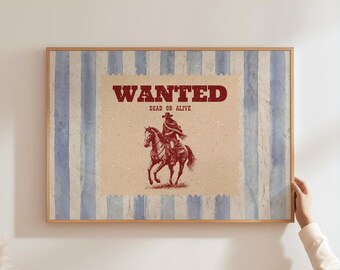 May include: Framed vintage-style print with a cowboy on horseback, set against a backdrop of blue and white stripes. The text "WANTED" in bold red letters is above "DEAD OR ALIVE".