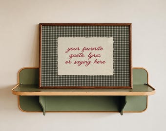 May include: A rectangular framed print featuring a dark green and white plaid background with a central cream-colored paper insert. The text "your favorite quote, lyric, or saying here" is printed in red cursive script on the insert.