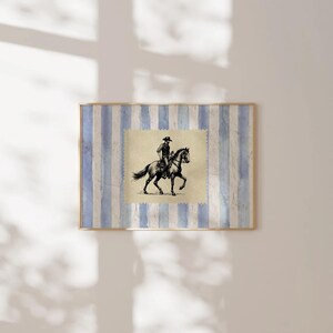 Pu&ograve; includere: Un'illustrazione in bianco e nero di un cowboy a cavallo. L'illustrazione &egrave; incorniciata e posizionata su uno sfondo di strisce blu e bianche.
