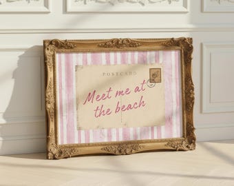 May include: A framed postcard with the text "Meet me at the beach" in a decorative gold frame. The postcard has a pink and white striped background and a vintage postage stamp.