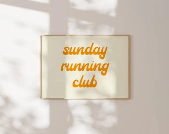 May include: A framed print with the text "sunday running club" in orange lettering on a white background.