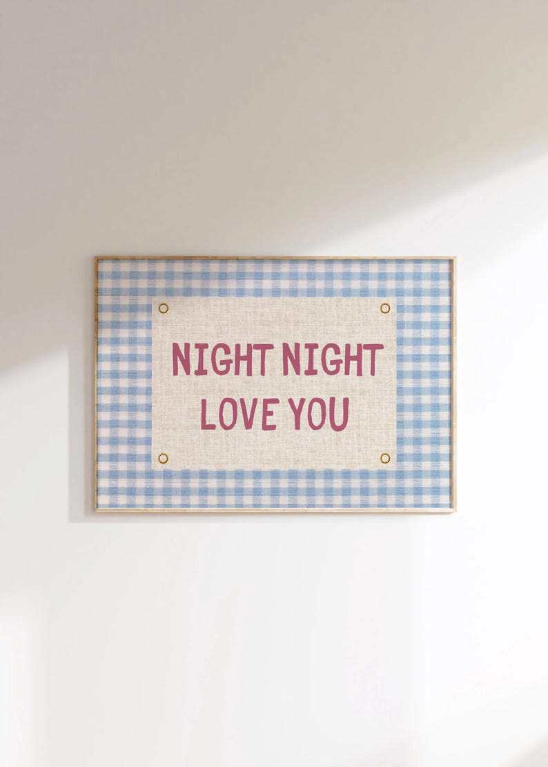 May include: A framed wall art piece with a light blue and white gingham pattern border. The center features a beige fabric with the words "NIGHT NIGHT LOVE YOU" in a dark pink font. The frame has a light wood finish.