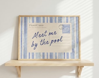 May include: Framed postcard print with the text "Meet me by the pool" in a handwritten style. The postcard has a vintage aesthetic with blue and white striped borders and a postage stamp design. The print is displayed on a wooden shelf.
