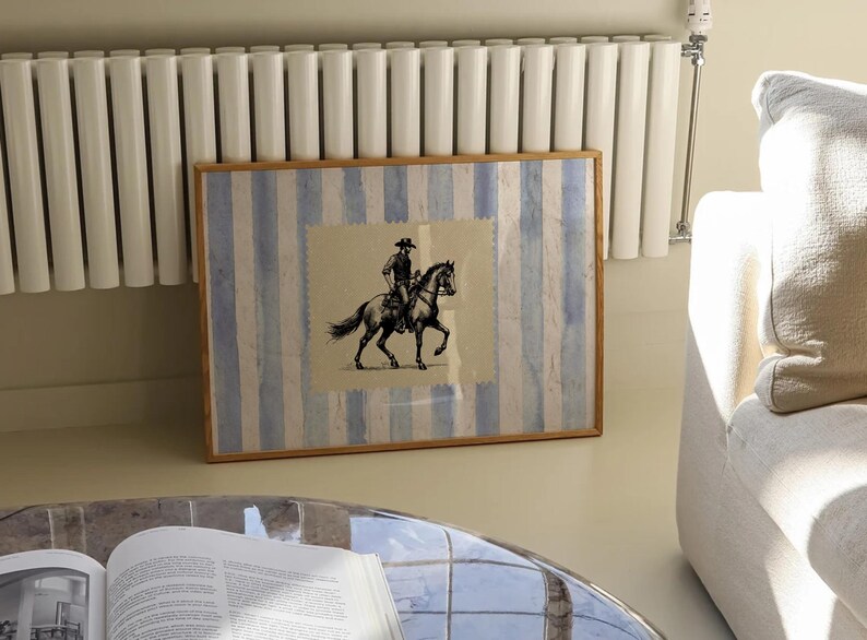 Pu&ograve; includere: Una stampa incorniciata di un'illustrazione in bianco e nero di un cowboy a cavallo. La stampa &egrave; su uno sfondo a strisce blu e bianche.