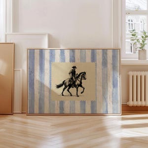 Pu&ograve; includere: Un'illustrazione in bianco e nero di un cowboy a cavallo su uno sfondo a strisce blu e bianche. L'illustrazione &egrave; incorniciata e sembra essere una stampa vintage.