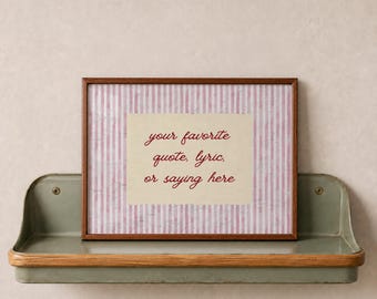 May include: A rectangular picture frame with a dark wood finish containing a print with vertical pink and white stripes and a central cream-colored rectangle featuring the red text: your favorite quote, lyric, or saying here.