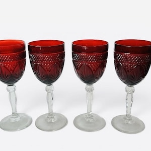 May include: A set of four ruby red glass goblets featuring a textured diamond pattern on the upper bowl and a pressed leaf design on the lower bowl. Each goblet has a clear glass stem with a decorative knob and a circular clear glass base.