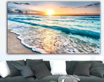 May include: A panoramic photograph of a beach scene with a sunrise over the ocean. The waves are crashing on the sandy shore, creating a foamy white edge. The sky is a vibrant mix of pink, orange, and blue.
