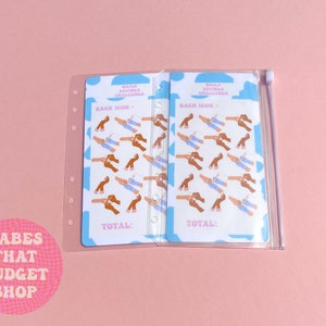 May include: A clear plastic zippered pouch with two sheets of stickers inside. The stickers are blue, pink, and white and feature illustrations of hands holding hands. The text on the stickers reads "Saila Savings Challenge" and "Each Icon = ".