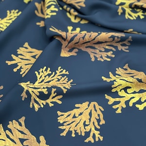 Pode incluir: Um tecido azul marinho com um padrão repetitivo de coral dourado. O tecido está dobrado e drapeado, mostrando a textura do material.