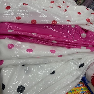 Puede incluir: Primer plano de varias telas con estampado de lunares. Las telas son blancas con lunares rojos, rosas y negros. Las telas están dobladas y apiladas, mostrando los diferentes colores y patrones.