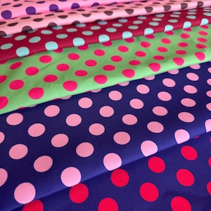 Könnte beinhalten: Eine Sammlung farbenfroher Stoffmuster mit Polka-Dots. Die Stoffe zeigen eine Vielzahl von Farben, darunter Blau, Rosa, Grün und Lila, jeweils mit kontrastierenden Polka-Dots. Die Stoffe sind geschichtet und zeigen die verschiedenen Farbkombinationen.