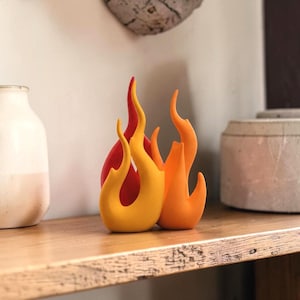Peut inclure: Une sculpture décorative en forme de flammes stylisées dans des tons vifs de rouge, d'orange et de jaune. L'objet présente des bords lisses, incurvés et pointus qui imitent l'apparence du feu, se tenant debout comme une pièce solide unique.