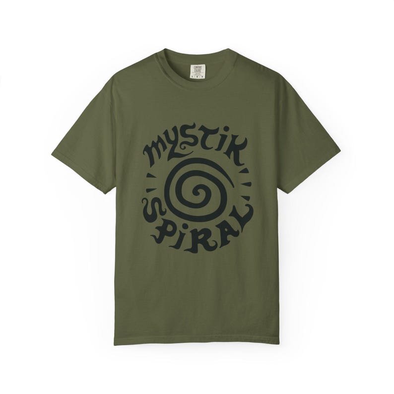 K&ouml;nnte beinhalten: Ein olivgr&uuml;nes Kurzarm-T-Shirt mit einem schwarzen Grafikdruck auf der Brust. Das Design besteht aus einer zentralen Spirale, die von dem Text "MYSTIK SPIRAL" in einer stilisierten, dekorativen Schriftart umgeben ist. Das T-Shirt hat einen Rundhalsausschnitt.