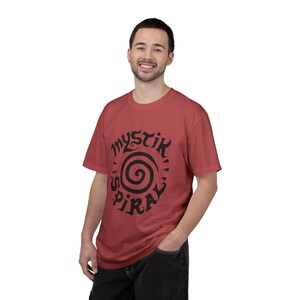 K&ouml;nnte beinhalten: Ein ziegelrotes Kurzarm-T-Shirt mit einem schwarzen Grafikdruck auf der Brust. Das Design besteht aus einer zentralen Spirale, umgeben von dem Schriftzug "MYSTIK SPIRAL" in einer stilisierten, fetten, dunklen Schrift. Das Shirt hat einen Rundhalsausschnitt.