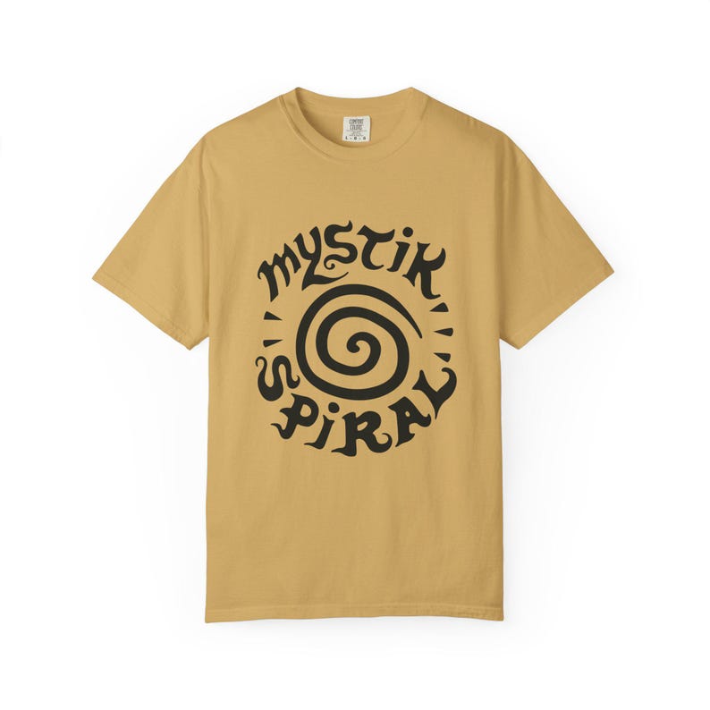 K&ouml;nnte beinhalten: Ein senfgelbes Kurzarm-T-Shirt mit einem schwarzen Grafikdruck auf der Brust. Das Design besteht aus einer zentralen Spirale, die von dem Text "MYSTIK SPIRAL" umgeben ist, welcher in einer stilisierten, dekorativen schwarzen Schriftart gehalten ist.